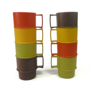 May include: Set of six stacking plastic cups in brown, orange, yellow, and green. The cups are designed to stack on top of each other.