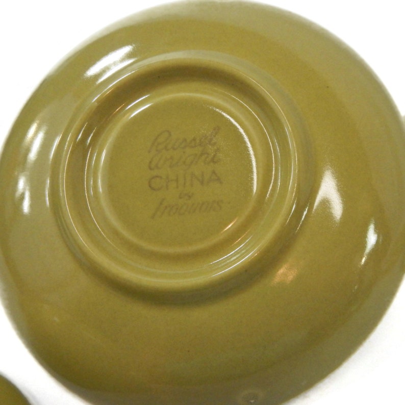 May include: A green saucer with the text "Russel Wright CHINA by Iroquois" printed on the bottom.