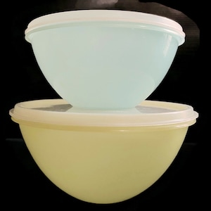 May include: Two plastic mixing bowls, one light blue and one yellow, are stacked on top of each other.