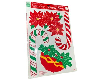 May include: A sheet of reusable vinyl Presto-Stick Window Decor featuring Christmas graphics. The designs include red poinsettias with green leaves, two candy canes with red and white or green and white stripes, and a red gift with a yellow bow and holly.