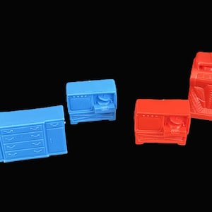 May include: A selection of miniature toy furniture in blue and red. The set includes a dresser, a microwave, a stove, and a radio. The toys are made of plastic against a black background.