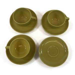 May include: Set of four green ceramic teacups and saucers. The cups and saucers are a muted olive green color.