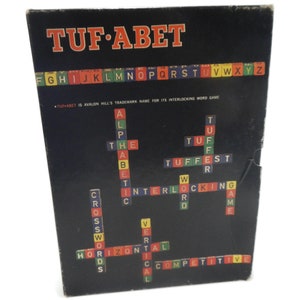 May include: A vintage game box for "TUF-ABET", an interlocking word game by Avalon Hill. The box features a black background with the game's name in red and white letters. The box also includes a sample crossword puzzle with the words "ALPHABET", "CROSSWORDS", "HORIZONTAL", "VERTICAL", "INTERLOCKING", "TUFFEST", "WORD", "GAME", and "COMPETITIVE".