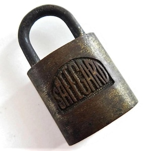 May include: A brass padlock with the word "SAFEGUARD" embossed on the front. The padlock is closed and has a tarnished finish.