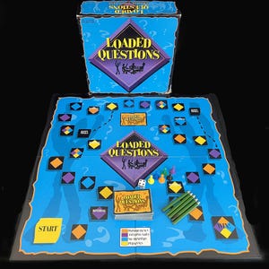 May include: A board game titled "Loaded Questions" with a blue game board, box, and cards. The game board features a path with colorful spaces, dice, pencils, and game pieces. The box and board display the game's logo in a diamond shape.