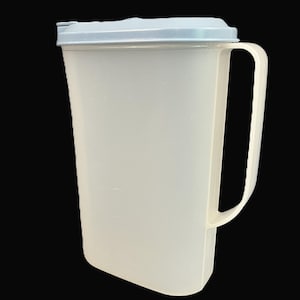 May include: A white plastic pitcher with a light blue lid and a large handle. The pitcher is rectangular with rounded corners and is designed for holding liquids. The handle is sturdy and easy to grip.