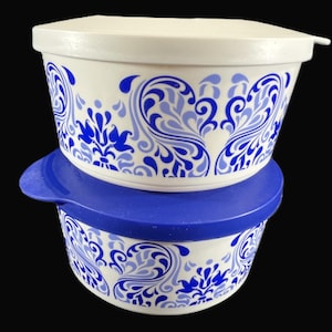 May include: Two white plastic storage containers with blue and white floral designs. The top container has a blue lid.