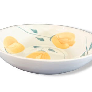 May include: White ceramic bowl with a floral design. The bowl features yellow flower illustrations with green stems and leaves. The bowl has a smooth, glossy finish and a slightly oval shape, suitable for serving salads or side dishes.