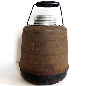 May include: A vintage metal thermos with a black handle and a rusty brown exterior. The thermos has a silver lid and a black base.