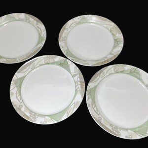 May include: Four white ceramic dinner plates with a green and gray floral design.