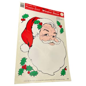 May include: Reusable vinyl window cling featuring a Santa Claus face with a red hat and white beard. The cling is labelled "Presto-Stick Window Decor" and "Visible Both Sides".