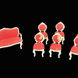 May include: Miniature red sofa and chairs with white trim. The set includes a small sofa and six chairs, all with a similar design. The furniture is set against a black background.