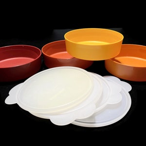 May include: Set of four colorful plastic bowls with lids. The bowls are orange, yellow, and red. The lids are white.