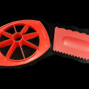 May include: Red plastic kitchen tool with a round cutter for slicing fruit and a separate red plastic scraper.