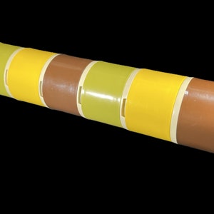 May include: A set of six colorful nesting storage containers. The containers are made of plastic and have a striped pattern in shades of brown, yellow, and green.