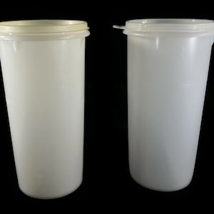 May include: Two white plastic containers with lids. The containers are cylindrical and have a smooth surface.