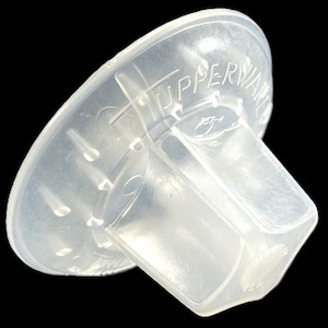 May include: A clear plastic bottle stopper with the text "UPPERWARE" embossed on the top.