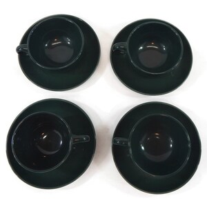 May include: Set of four dark green ceramic teacups and saucers. The cups and saucers are a deep forest green color.