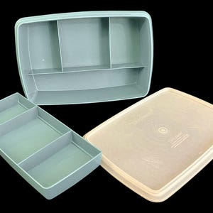 May include: Three-piece set of vintage Tupperware storage containers in shades of blue and beige. The set includes a rectangular container with a lid, and two divided trays. The containers are made of durable plastic.