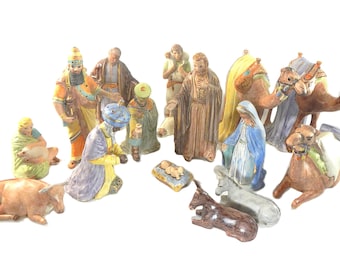 May include: A nativity scene set with 14 ceramic figurines, including the three wise men, Mary, Joseph, baby Jesus, a donkey, a cow, and three camels. The figurines are painted in bright colors and have detailed features.