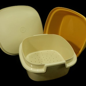 May include: A two-piece set of yellow and off-white plastic kitchen containers with a strainer. The top container is yellow and the bottom container is off-white with a strainer.