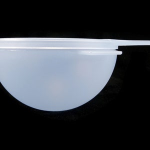 May include: A white plastic bowl with a lid and a handle. The bowl is round and has a smooth surface.
