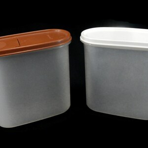 May include: Two clear plastic containers with lids. One container has a brown lid and the other has a white lid.