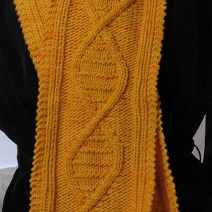 May include: A yellow knitted scarf with a cable knit pattern.