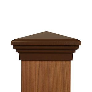 May include: A brown post cap with a pyramid-shaped top and decorative molding. The cap is designed to fit on top of a wooden post, providing a finished look. The cap is made of a durable material and is designed to withstand the elements.