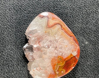 May include: A clear quartz crystal with a red, orange, and brown agate center. The crystal has a rough, natural texture.