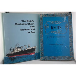 May include: Two vintage books. The book on the left is titled "The Ship's Medicine Chest and Medical Aid at Sea" with a ship illustration. The book on the right is titled "Knots useful & ornamental". Both books are blue.