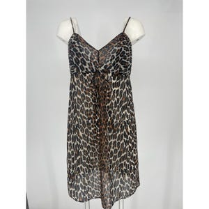 May include: A sleeveless dress with a V-neckline and spaghetti straps. The dress features a brown and black leopard print pattern. A tie detail is at the waist. The dress is displayed on a white mannequin.