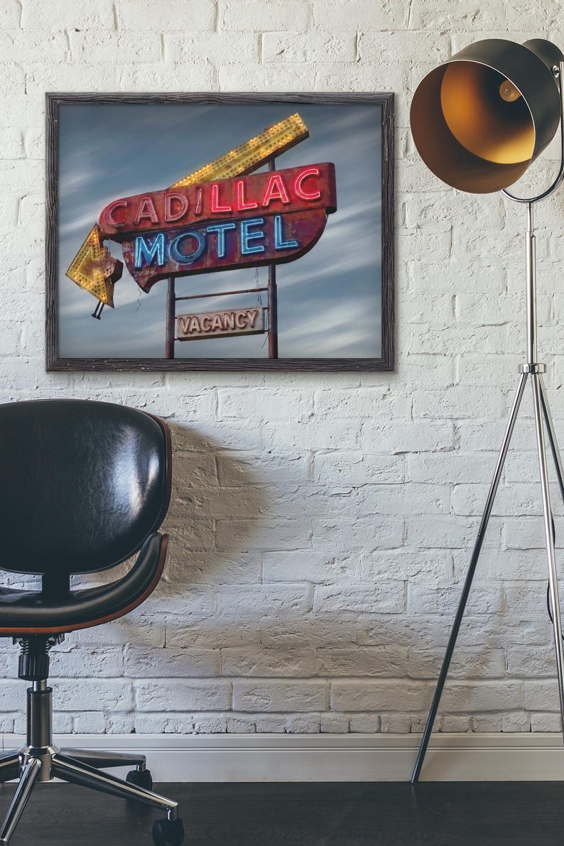 K&ouml;nnte beinhalten: Ein gerahmter Kunstdruck mit einem alten Cadillac Motel Neonschild mit roter und blauer Schrift, einem gelben Pfeil und einem kleinen rechteckigen Schild darunter mit der Aufschrift VACANCY vor einem bew&ouml;lkten Himmel in einem Raum.