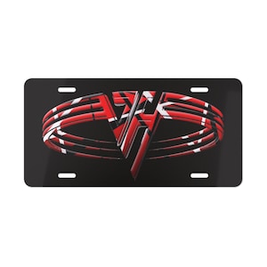 May include: Black license plate featuring a red, white, and black graphic design. The design includes the letters "VH" in a stylized font, with red and white stripes. The license plate has four mounting holes.