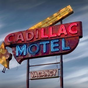 K&ouml;nnte beinhalten: Ein altes Cadillac Motel-Schild aus Metall mit roter Neon-Schrift f&uuml;r Cadillac und blauer Neon-Schrift f&uuml;r Motel. Das Schild enth&auml;lt einen gelben Pfeil, der nach unten zeigt, und ein kleineres rechteckiges Schild darunter mit der Aufschrift Vacancy.