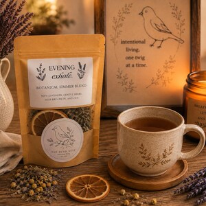 Può includere: Una busta color marrone chiaro con l'etichetta EVENING exhale. BOTANICAL SIMMER BLEND contenente una fetta di arancia essiccata ed erbe. Accanto si trovano una tazza in ceramica maculata con tè su un sottobicchiere in legno, una candela e un quadro.