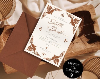 May include: A wedding invitation featuring the names "Estelle & David" in a stylish script, framed by floral and bird designs. The invitation has a cream base with brown details, alongside a coordinating envelope.