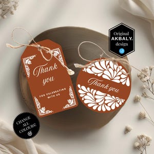 Op de afbeelding: Twee terracotta cadeaulabels met witte bloemmotieven en de woorden "Thank you". Eén label is rechthoekig, de andere rond. Beide hebben touw om op te hangen. Het rechthoekige label zegt ook "For celebrating with us."