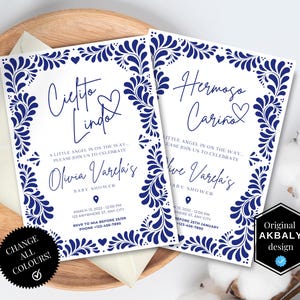 Puede incluir: Dos invitaciones de baby shower con un borde de diseño floral azul y texto en español. Las invitaciones dicen "Cielito Lindo" y "Hermoso Cariño". Las invitaciones están sobre una bandeja de madera con un sobre.
