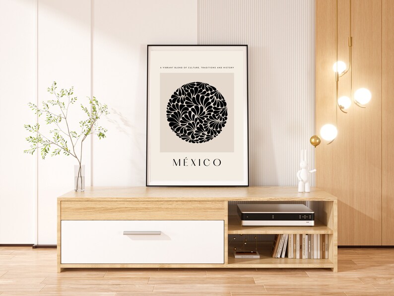 Puede incluir: Un mueble de TV de madera clara con un caj&oacute;n blanco, dos estantes y una impresi&oacute;n enmarcada en negro con un dise&ntilde;o floral en blanco y negro y la palabra "M&Eacute;XICO".