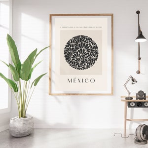 Puede incluir: Un p&oacute;ster minimalista con un dise&ntilde;o floral en blanco y negro en un c&iacute;rculo, con la palabra "M&Eacute;XICO" en texto negro debajo del c&iacute;rculo. El p&oacute;ster est&aacute; enmarcado en madera y cuelga de una pared blanca.