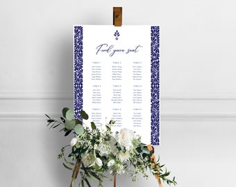 May include: A white wedding seating chart with a navy blue floral border. The chart is titled "Find your seat" and lists the names of guests assigned to each table.