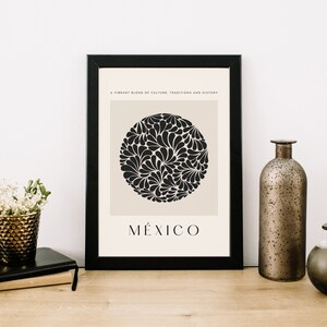 Puede incluir: Una impresi&oacute;n enmarcada en blanco y negro con un fondo beige. La impresi&oacute;n presenta un c&iacute;rculo negro con un patr&oacute;n floral estilizado y la palabra "M&Eacute;XICO" en texto negro debajo del c&iacute;rculo. El texto sobre el c&iacute;rculo dice "Una mezcla vibrante de cultura, tradiciones e historia."