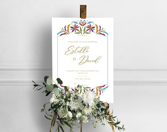 May include: A white wedding welcome sign with a colorful floral border. The sign reads "Welcome to our wedding Estelle & David Thank you for celebrating with us 10.25.2021".