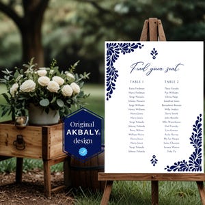 Peut inclure: Un tableau de mariage blanc avec des motifs floraux bleus. Le tableau est intitul&eacute; "Find your seat" et liste les noms pour deux tables, Table 1 et Table 2.