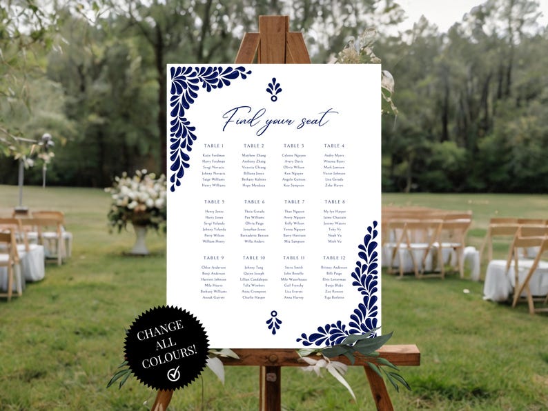 Peut inclure: Un plan de table de mariage blanc avec un motif floral bleu marine. Le plan est intitul&eacute; "Find your seat" et liste les noms des invit&eacute;s par num&eacute;ro de table. Le plan est affich&eacute; sur un chevalet dans un jardin.
