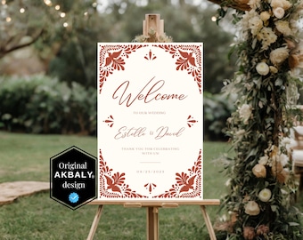 May include: A white welcome sign with a red floral design and the text "Welcome to our wedding Estelle & David Thank you for celebrating with us 09/05/2023"