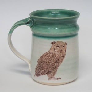 May include: A ceramic mug with a green glaze and a brown owl illustration. The owl is facing to the right and has a white background.