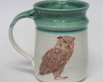May include: A ceramic mug with a green glaze and a brown owl illustration. The owl is facing to the right and has a white background.