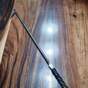 May include: A long, thin, metal tool with a pointed end and a twisted handle. The handle has a black finish and a ring at the end.